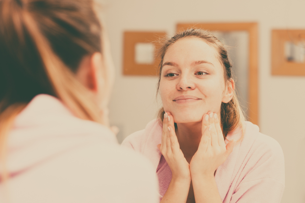 Une jeune femme nettoie sa peau durant son soin du visage de routine quotidienne